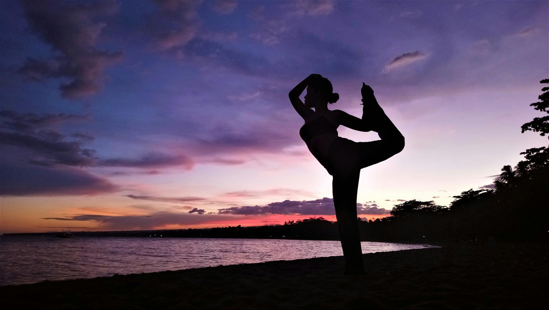 a silhouette of a woman doing yoga at the beach